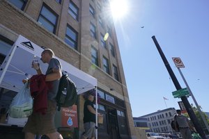 A person walks away after being given bottles of water, Monday, June 28, 2021, at a hydration station in front of the Union Gospel Mission in Seattle