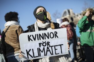 A woman holds a banner reading "Women for climate" in Danish as a reference to Greta Thunberg, as protesters and activists gather at Republique square on the eve of the International Women's Day in Paris, Sunday, March 7, 2021