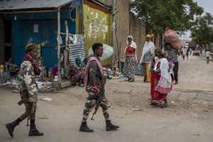 In this Friday, May 7, 2021 file photo, fighters loyal to the Tigray People's Liberation Front (TPLF) walk past women selling foodstuffs on the street in the town of Hawzen, then-controlled by the group but later re-taken by government forces, in the Tigray region of northern Ethiopia