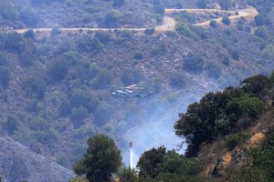 An helicopter drops water over the mountain of Troodos in Agious Vavatsinias village, southwestern Cyprus, Sunday, July 4, 2021.