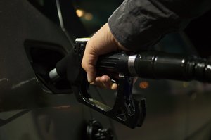 Person holding gasoline nozzle at gas station