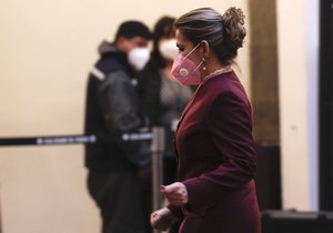 Bolivia's interim President Jeanine Anez, wearing a face mask amid the COVID-19 pandemic, walk after enacting a law to hold elections at the government palace in La Paz,  Bolivia, Thursday, Aug. 13, 2020.