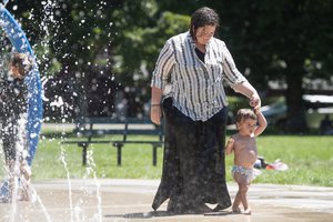 Jenny Rol, right, holds her 14-month-old daughter Safi in a water feature to cool off at a park in Missoula, Montana, as temperatures approached 100 degrees on Wednesday, June 30, 2021