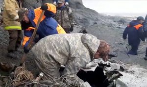 This photo taken from video released by the Russia Emergency Situations Ministry press service on Wednesday, July 7, 2021, shows Emergency Situations Ministry workers at the wreckage of a missing Antonov An-26 missing plane found near its destination airport outside the town of Palana, in Russia's Far East.