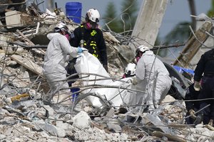 Rescue workers use a tarp for recovered remains at the site of the collapsed Champlain Towers South condo building, Monday, July 5, 2021 in Surfside