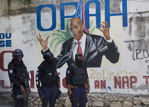 Police stand near a mural featuring Haitian President Jovenel Moise, near the leader’s residence where he was killed by gunmen in the early morning hours in Port-au-Prince, Haiti, Wednesday, July 7, 2021