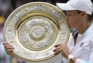 Australia's Ashleigh Barty poses with the trophy for the media after winning the women's singles final after defeating the Czech Republic's Karolina Pliskova on day twelve of the Wimbledon Tennis Championships in London, Saturday, July 10, 2021