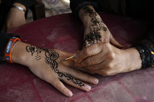 A Palestinian woman demonstrates the painting of a traditional henna tattoo at the Palestinian Heritage Exhibition in the town of Khan Yunis, in the southern Gaza Strip on October 16, 2012. Palestinians attend the Heritage Exhibition every year to remember the ancient civilizations. At the festival, Palestinian women paint henna tattoos on each other a on the second day of the festival.Photo by Ahmed Deeb / WN