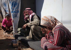 File - Syrian refugees Um Loay, 60, right, the wife of Dahi al-Hammadi, 74, center, from Deir al-Zour, speaks to The Associated Press at Zaatari Refugee Camp near the Syrian border, in Mafraq, Jordan, Wednesday, Feb. 12, 2014.