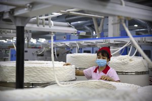 A worker watches as a machine processes cotton yarn at a Huafu Fashion plant, as seen during a government organized trip for foreign journalists, in Aksu in western China's Xinjiang Uyghur Autonomous Region, Tuesday, April 20, 2021