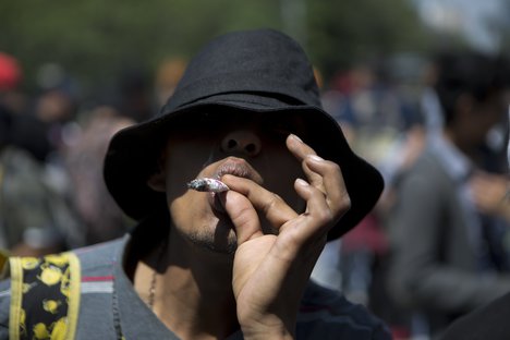 A young man smokes a marijuana cigarette during a celebration marking Cannabis International Day in Mexico City, Friday, April 20, 2018.