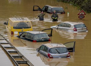 Helpers check for victims in flooded cars on a road in Erftstadt, Germany, Saturday, July 17, 2021.