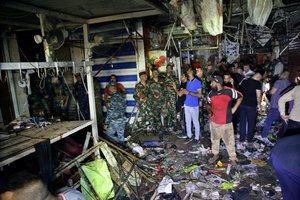 People and security forces gather at the site of a bombing in Wahailat market in Sadr City, Iraq, Monday, July 19, 2021