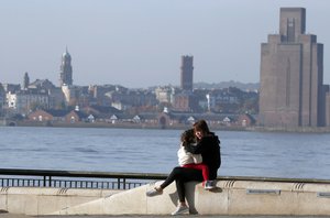 A mother sits with her daughter near the river Mersey as new measures across the region are set to come into force in Liverpool, England, Wednesday, Oct. 14, 2020