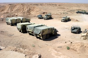 A US Marine Corps (USMC) Humvee (right), sits with several Ukraine Army Ural–4320-10 (6x6) 4,500kg trucks, and equipment trailers at a vehicle staging park located at Badrah, Iraq