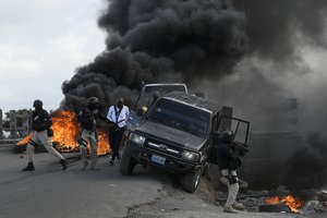 Police abandon their vehicle during a demonstration that turned violent in which protesters demanded justice for the assassinated President Jovenel Moise in Cap-Haitien, Haiti, Thursday, July 22, 2021