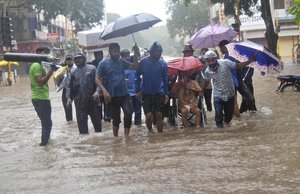 A man wearing an oxygen mask is helped on a wheelchair through floodwaters in Kolhapur, in the western Indian state of Maharashtra, Friday, July 23, 2021