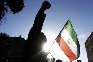 A demonstrator shouts slogans near the flag of the former Imperial State of Iran as he gathers with supporters of Maryam Rajavi, head of the Iranian opposition group National Council of Resistance, outside the Iran Embassy, in Rome, Tuesday, Jan. 2, 2018.