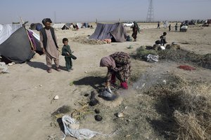 An internally displaced Afghan woman who fled her home due to fighting between the Taliban and Afghan security personnel, burns thorny twigs to make tea in a makeshift tent camp on a rocky patch of land on the edge of the city of Mazar-e-Sharif, northern Afghanistan, Thursday, July 8, 2021.