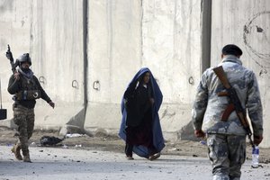 File - An Afghan woman walks near the attack site  in Kabul, Afghanistan, Tuesday, Jan. 15, 2019. A Taliban suicide bomber detonated an explosive-laden vehicle in the capital Kabul on Monday evening, according to officials.