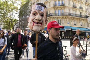 A protestor holds a puppet head depicting French President Emmanuel Macron during a demonstration in Paris, France, Saturday, July 31, 2021