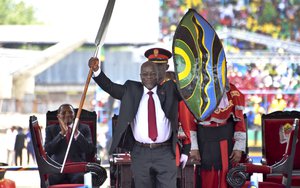 Tanzania’s new President John Pombe Magufuli holds up a ceremonial spear and shield to signify the beginning of his presidency, shortly after swearing an oath during his inauguration ceremony at Uhuru Stadium in Dar es Salaam, Tanzania Thursday, Nov. 5, 2015.