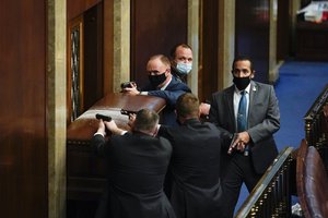 File - U.S. Capitol Police with guns drawn stand near a barricaded door as protesters try to break into the House Chamber at the U.S. Capitol on Wednesday, Jan. 6, 2021, in Washington.