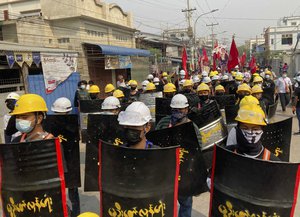 Protesters march with makeshift shields on main road during a demonstration in Mandalay, Myanmar, Monday, March 8, 2021. The escalation of violence in Myanmar as authorities crack down on protests against the February 1 coup is adding to pressure for more sanctions against the junta. (AP Photo)