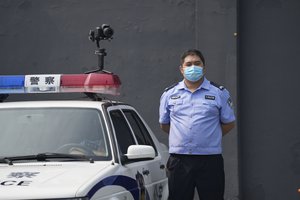 A policeman wearing a face mask stands guard next to a police vehicle with a camera outside a detention center where Dominic Barton, Ambassador of Canada to China will meet Canadian Michael Spavor, in Dandong, China, Wednesday, Aug. 11, 2021