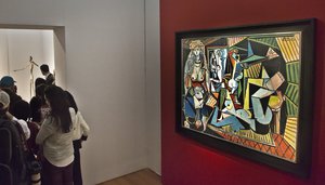 Visitors are introduced to the bronze sculpture "L'homme au doigt" by Alberto Giacometti, left, after viewing the Pablo Picasso oil painting "Les femmes d'Alger," right, during Christie's Spring 2015 Evening Sale press preview, Friday, May 1, 2015, in New York.