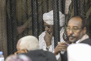 Sudan's autocratic former President Omar al-Bashir sits in a cage during his trial on corruption and money laundering charges in Khartoum, Sudan, Saturday, Aug. 24, 2019.