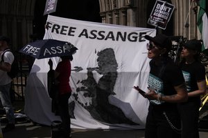 Supporters of WikiLeaks founder Julian Assange stand in front of a banner bearing an image of him, during the first hearing in the Julian Assange extradition appeal, at the High Court in London, Wednesday, Aug. 11, 2021