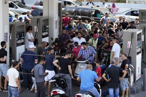 FILE- In this June 27, 2021 file photo, motorcycle drivers wait to get fuel at a gas station in a southern suburb of Beirut, Lebanon.