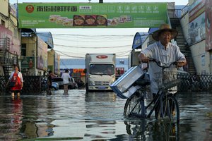 In this Monday, July 26, 2021 file photo, a man carries goods on his bicycle as he walks out of the the Yubei Agricultural and Aquatic Products World in Xinxiang in central China's Henan Province