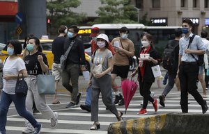 People wear face masks to help protect against the spread of the coronavirus as they cross an intersection in Taipei, Taiwan, Wednesday, Aug. 11, 2021