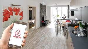 Person holding smartphone with Airbnb logo