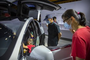 File photo: Visitors wearing face masks to protect against the coronavirus look at a Tesla vehicle on display at the China International Fair