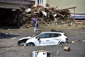 A man checks his car buried in the mud after floods and mudslides killed about three dozens of people, in Bozkurt town of Kastamonu province, Turkey, Friday, Aug. 13, 2021