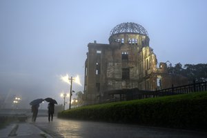 Men walk in a heavy rain near the Atomic Bomb Dome in Hiroshima, western Japan Thursday, July 15, 2021.