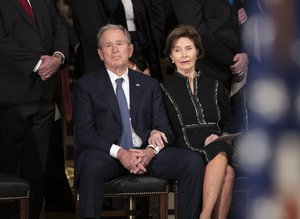 Former President George W. Bush, with former first lady Laura Bush, listens to eulogies for his father