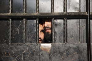 Taliban prisoners watch through the door inside the prison after an attack in the city of Jalalabad, east of Kabul, Afghanistan, Monday, Aug. 3, 2020.