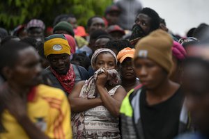 Residents watch an excavator remove rubble from a collapsed building three days after a 7.2 magnitude quake in Les Cayes, Haiti, Tuesday, Aug. 17, 2021