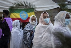 Ethiopians queue to cast their votes in the general election, next to a national flag, at a polling center in the capital Addis Ababa, Ethiopia, Monday, June 21, 2021