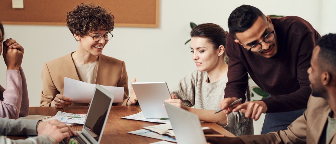 photo of a team of people working together around a desk all with their laptops