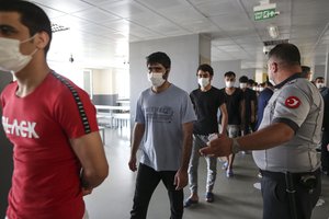 Migrants, mainly coming from Afghanistan, queue for lunch at a deportation center in Turkish city of Van that borders Iran, Turkey, Sunday. Aug. 22, 2021