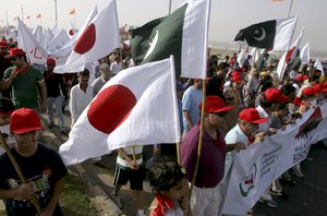 Pakistani families carrying Japanese flags take part in a rally organized by Pakistan-Japan Cultural Association in the memory of earthquake and tsunami victims, Sunday, March 20, 2011