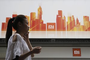 In this Wednesday, June 20, 2018, photo, a woman walks past a Xiaomi store in Hong Kong