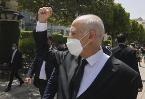 Tunisian President Kais Saied raises his fist to bystanders as he stroll along the avenue Bourguiba in Tunis, Tunisia, Sunday, Aug. 1, 2021