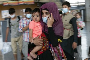 Families evacuated from Kabul, Afghanistan, walk through the terminal before boarding a bus after they arrived at Washington Dulles International Airport, in Chantilly, Va., on Monday, Aug. 23, 2021