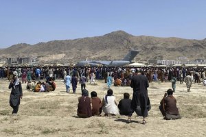 FILE - In this Monday, Aug. 16, 2021 file photo hundreds of people gather near a U.S. Air Force C-17 transport plane along the perimeter at the international airport in Kabul, Afghanistan.